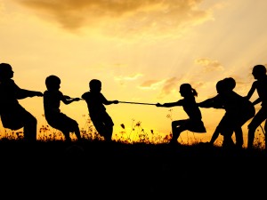 Silhouette, group of happy children playing on meadow, sunset, summertime